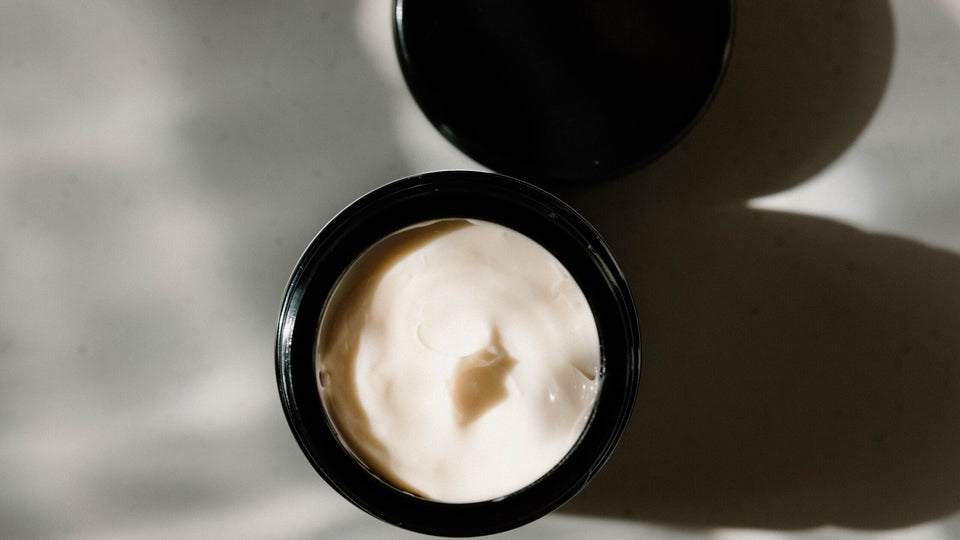 An open jar of SoBotanical Moisture Extreme Cream in dappled window light