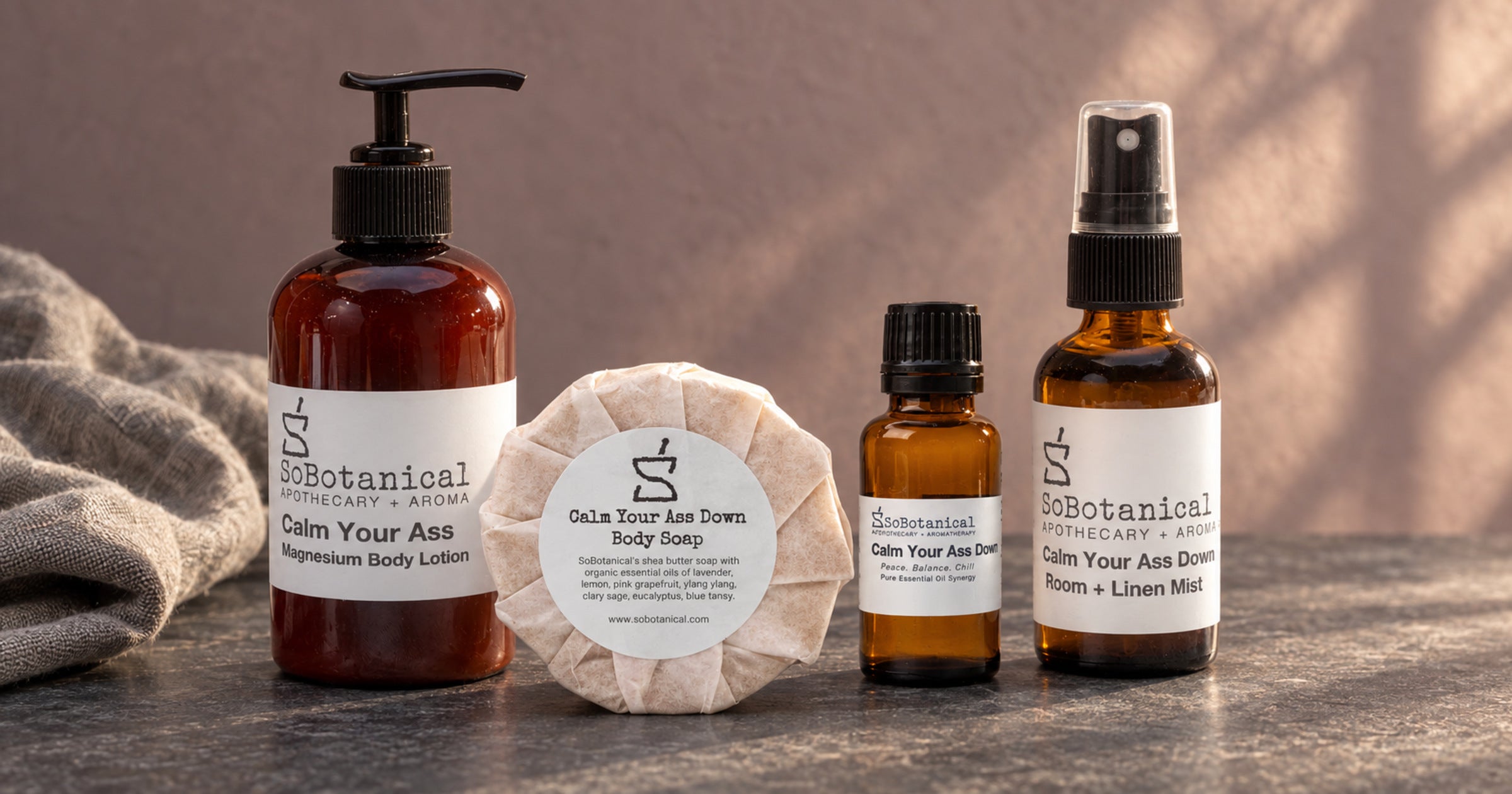 Calm Your Ass Down lotion, body soap, synergy and room mist on grey stone.