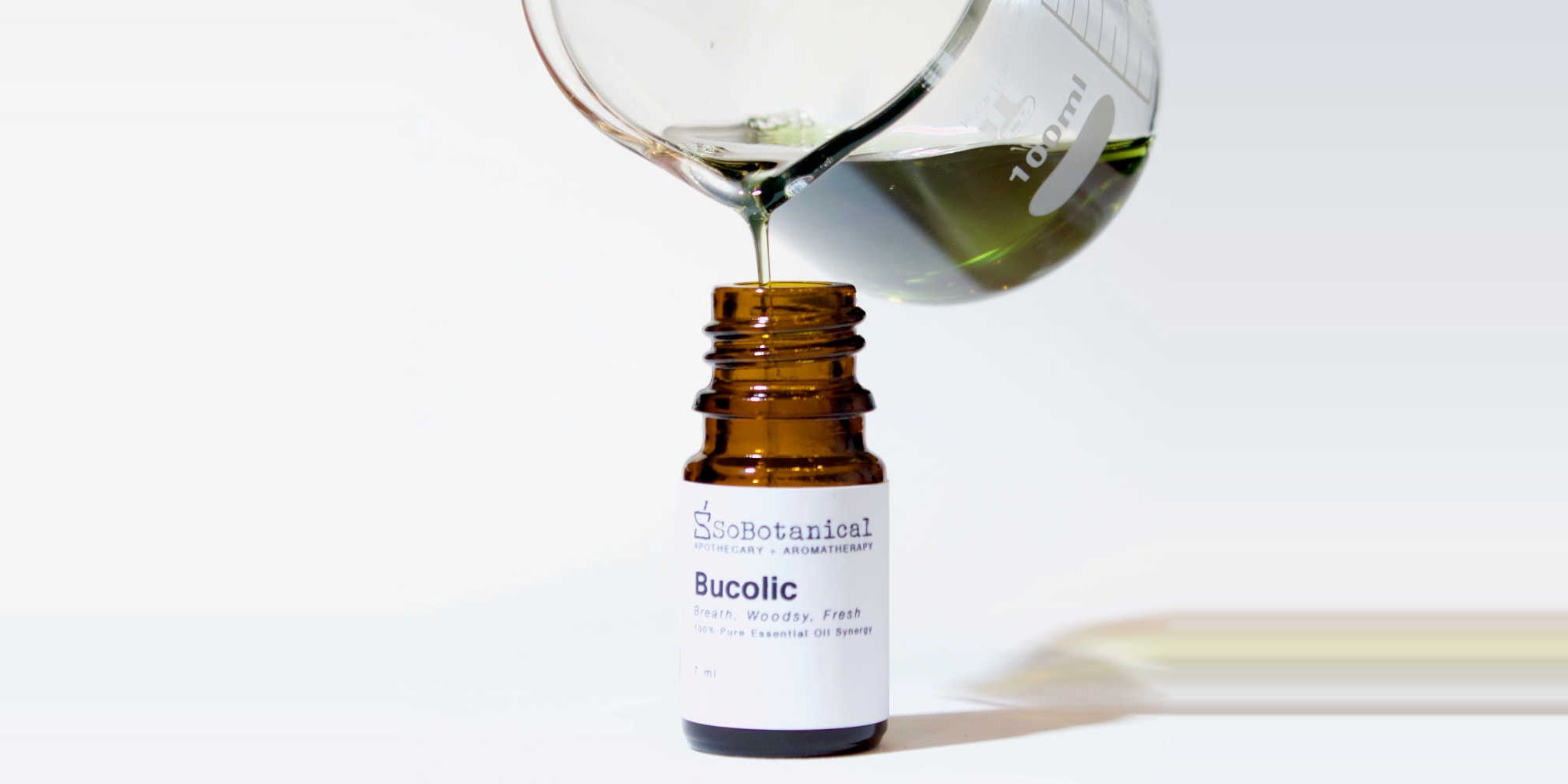 Bucolic synergy blend poured from a glass beaker into an amber bottle