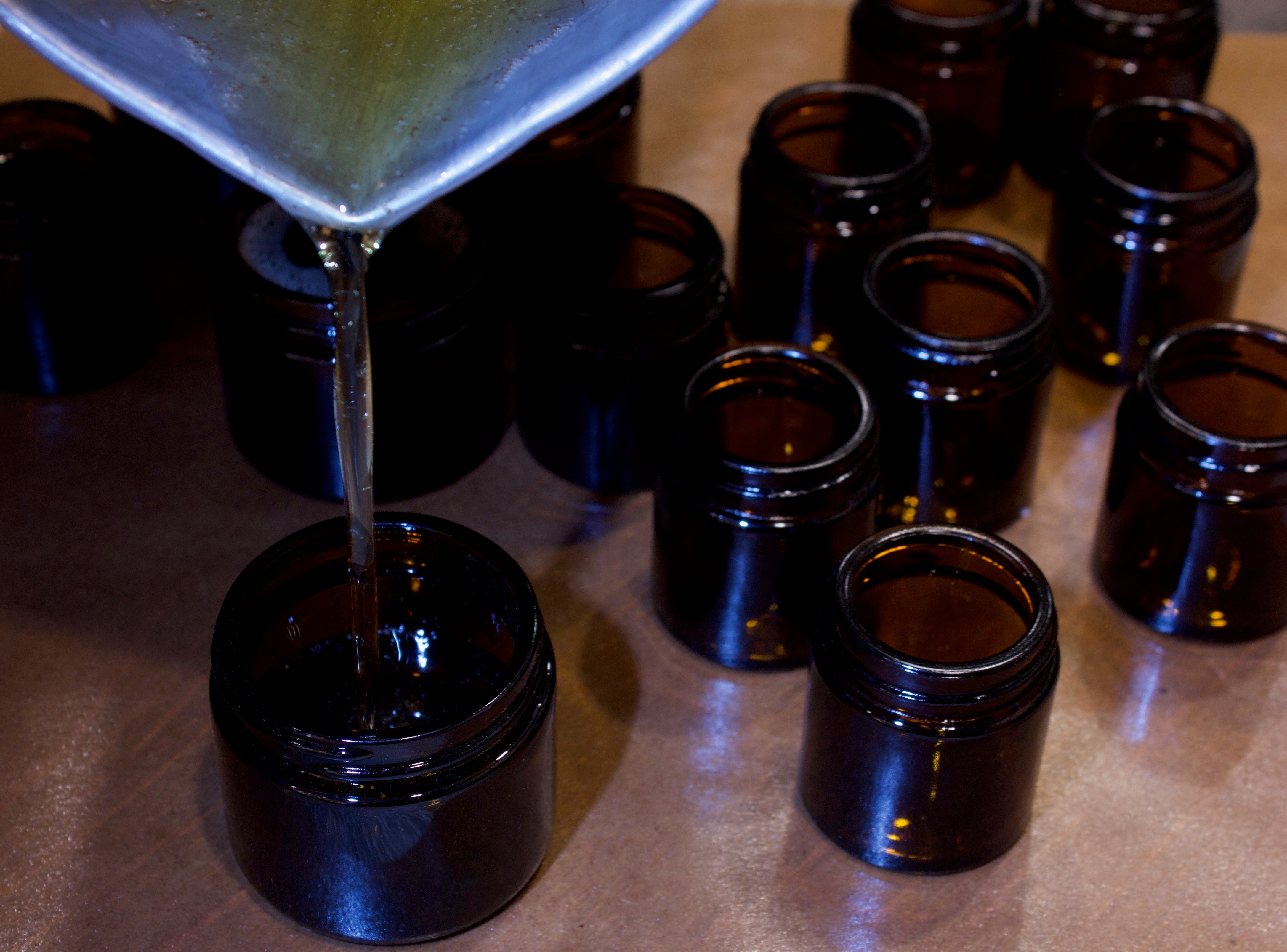 Pouring into multiple amber jars at the apothecary